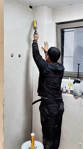 installing white pvc wall panels in a bathroom corner and applying silicone sealant to the edges