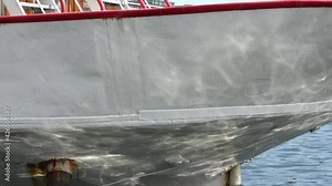 Close up view at the front of a boat with caustic sunlight reflections of water