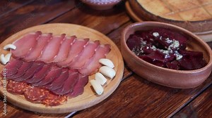 Cured meat delicacies arranged on a wooden platter. Garlic and home made bread and beet in shot.