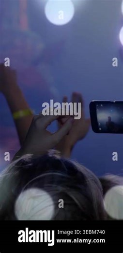 Vertical video: Front-row crowd raising hands, raising phone and tapping screen to record concert. Smartphone, audience, silhouette, bokeh, stage, haze, vertical video Stock Video Footage - Alamy