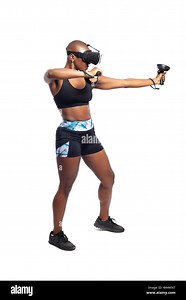 Black female wearing virtual reality headset pretending to draw a bow and playing a VR archery video game.  She is aiming at a target. Depicts esports Stock Photo - Alamy