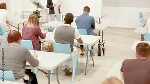 Female speaker giving presentation for adult students in lecture hall