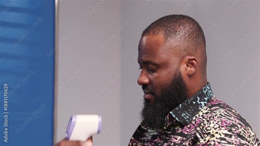 African male doctor uses a non-contact thermometer to check a male patient's temperature during a consultation in a hospital