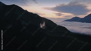 Aerial: Flying over the volcanic cone with steam coming from it on Mt Batur. In the background is the active volcano of Mt Agung. Bali, Indonesia