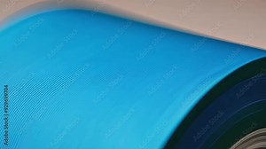 Close up of blue ink being applied to paper in a printing press, showcasing the manufacturing process of printed materials