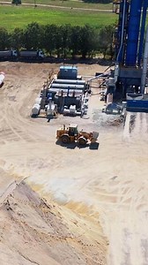 Modern asphalt plant among piles of rubble. Bulldozer working on the territory of asphalt factory. Aerial view. Vertical