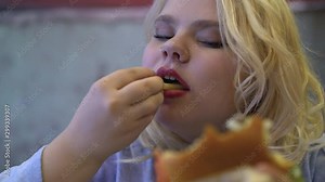 Young woman overeating high-calorie fast food, unhealthy nutrition, obesity risk
