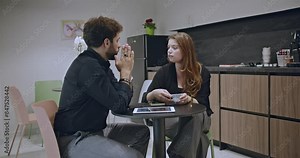 Colleagues have a serious discussion in a modern office break room over coffee, emphasizing workplace communication and professional relationships.