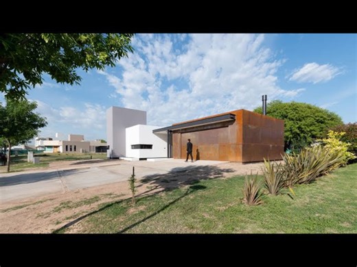 L-shaped house with a corten steel extension and a large courtyard tree
