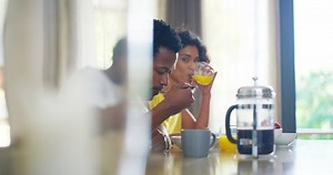 Couple, flirt and eating at table, sexy and happy together in home, smile and relax with fruit, marriage and kitchen. Black man, woman and flirting, love and seductive with strawberry and seduce