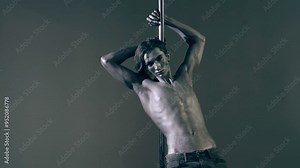 A guy model with a silvery body with art poses working on a pylon. Concept of work of models. Dancing on the pylon.