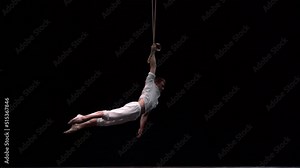 Muscular circus artist perform on the aerial straps on black background. Movement, strength concept