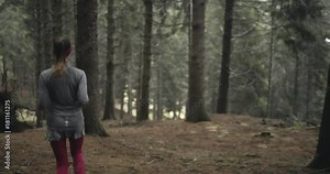 Athlete girl running through forest woods.Following behind.Real people woman runner sport training in autumn or winter in wild mountain outdoors nature, bad foggy weather.4k 60p slow motion video