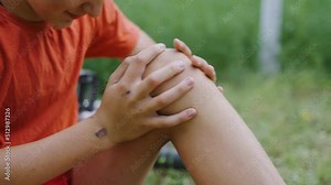 Wound on the knee. Pain from the received blow. The boy cries because of the fall. Accident with a bicycle. An accident in the park. The child cries because his leg hurts. Pity for an injured child.