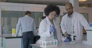 Scientist Meeting and Looking trough Microscope in Pharmaceutical Laboratory