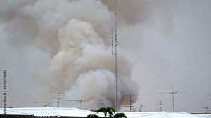 Burning house causes a big pile of smoke, black smoke rising up to blue sky background