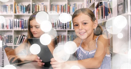 Two girls typing and tapping laptop, tablet in library, bokeh overlay drifting, right girl smiling