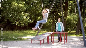 Children having fun is riding zipline. Cute girl and teen boy moving on zip line at playground - outdoors. Stock Video