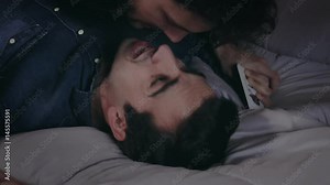 Close up gay couple on the bed who lit and then kisses gently