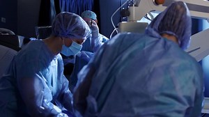 Diverse surgeons wearing surgical gowns operating on patient in operating theatre, slow motion. Hospital, surgery, teamwork, medicine, healthcare and work, unaltered. High quality 4k footage