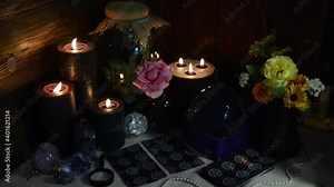 Mysterious still life with tarot cards, black candles and crystal ball on witch table. Esoteric, gothic and occult background with magic objects. Halloween fortune telling concept.