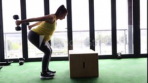Pregnant female model working out with weights in a gym to keep fit in her fourth trimester