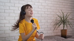 clip-1077374834-joyful-karaoke-home-happy-smiling-teen-hold
