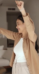 Cheerful beautiful young Vietnamese woman dancing to music at home, having fun, enjoying favorite songs, active leisure, party for one, celebrating success, smiling, feeling joy, stress relief