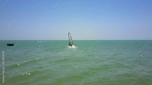 windsurfer with transparent sail starts moving from beach