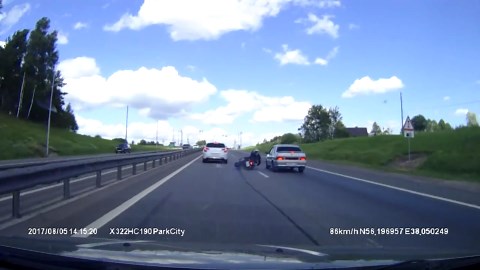 Motorcyclist crashes and almost gets run over by passing vehicle