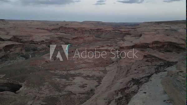 Paraglider With Colorful Chute Flying Over Canyons In Utah, USA. tracking shot
