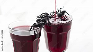 Background for Halloween masquerade party. Red drink - blood in glass goblets on a table with drinking spiders. Drink for a masquerade. congratulations happy halloween