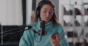 Pretty Young Positive Woman Radio Host Wearing Headphones Working from Home. Attractive and Confident Young Woman Trainer Making Podcast for Followers.