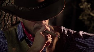 Cowboy with a cigar in the forest at night. Life in the wild west of America. 4K
