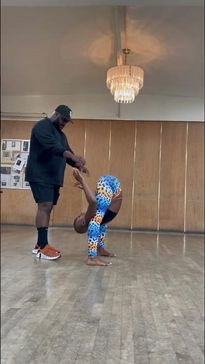 Man Holds Woman’s Hands While She Balances Her Feet on His After Bending Forward - 1271848-1