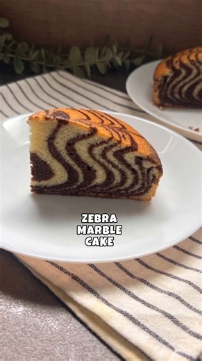ZEBRA MARBLE CAKE : Eggs: 4 Sugar: 1 cup (200g) Vanilla essence: 2 teaspoons Oil: 3/4 cup ( 125ml) Milk: 3/4 cup (180ml) All purpose flour: 2 cups (240g) Baking powder: 2 teaspoon Salt: a pinch Coco powder: 2 tablespoons INSTRUCTIONS: • Preheat your oven to 160°C and grease or line an 8” round cake pan. • In a large bowl, whisk the eggs and sugar until the mixture becomes light, pale, and slightly fluffy. • Add vanilla essence, oil, and milk, then mix well until fully combined. • In a separate b