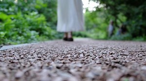 Legs of a woman in a long dress walking along the path. Close-up