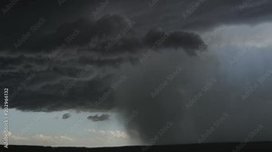 Fast-moving turbulent thunderstorm drag a rainstorm across a dark line of landscape, time lapse