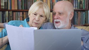 Senior couple at home using laptop. Retired family working with documents on computer. Computer literacy among elderly people, active modern lifestyle on retirement
