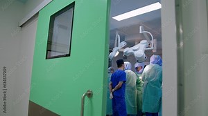 Footage at doors to a modern surgery room. Large team of doctors working in the trauma operation.