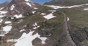 Car and motorbikes going up on curvy mountain road. Aerial view of Beartooth Highway in early summer, Wyoming