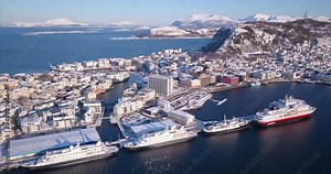 Alesund, Norway's most unique town with its art nouveau buildings and the amazing nature, fjords, mountains are shown in this cinematic, panning aerial time lapse in sunny but snowy winter time.
