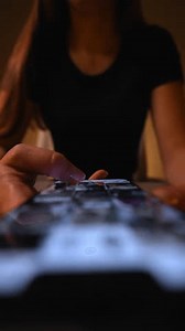 Vertical tomada desde arriba de una mujer mirando y leyendo noticias en línea en un teléfono inteligente, desplazándose hacia arriba y hacia abajo mirando en la pantalla del teléfono, navegando por las redes sociales en la habitación oscura. Disparando en cámara lenta.