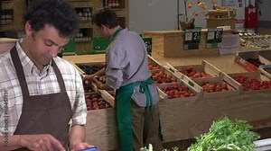 Grocery store employee reading inventory list on digital tablet