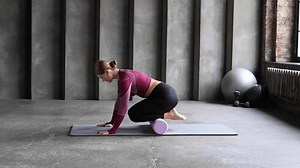 A woman performs a myofascial massage of the lower leg muscles with a roller.