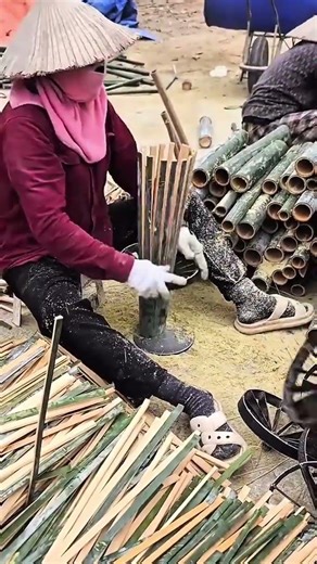 workers using a specialized machine to split bamboo into thin strips