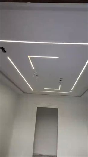Plaster of Paris & Drywall on Instagram: "This ceiling design incorporates multiple recessed channels with LED strip lights, forming linear and angular patterns. The central pattern comprises straight lines running lengthwise, punctuated by sharp 90° turns that create a geometric frame. Additional vertical LED strips positioned near the top left wall corner provide a decorative flourish."