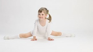 Smiling little girl doing the splits on white background