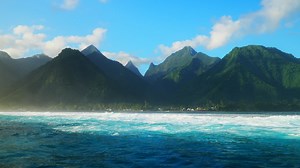 Towering mountain peaks surfing surf calm waves Teahupoo Tahiti French Polynesia crashing swell on shallow coral reef South Pacific island  ocean waterhousing landscape blue sky super slow motion | Premium Stock Video Footage