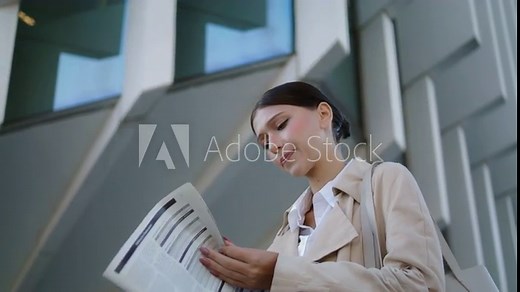 Woman turning newspaper pages standing outdoors close up. Businesswoman reading